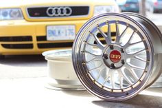 some wheels are sitting on the ground next to each other in front of a yellow car