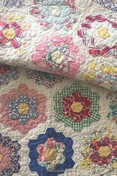 an old quilt is laying on top of a tablecloth with colorful flowers and gingham