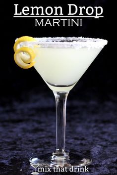 a white cocktail with lemon garnish in a coupe glass on a dark background