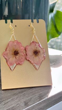 pink flower earrings sitting on top of a wooden table