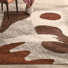 a brown and white area rug with an abstract design in the middle on a wooden floor