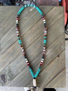 a necklace with beads is hanging on a wooden table next to a pair of shoes