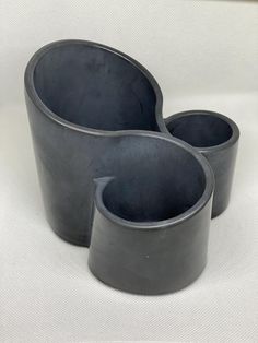 three black vases sitting next to each other on a white surface