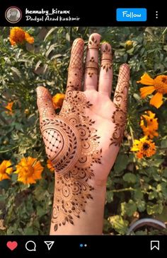 a person's hand with henna on it and yellow flowers in the background