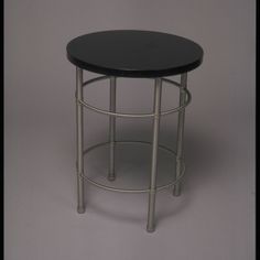 a small round table with metal legs and a black top