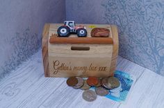 a wooden box filled with coins next to a small toy tractor