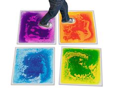 a young child standing on four square coasters with different colors and shapes in them