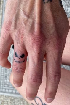 a man's hand with a smiley face tattoo on it and his fingers crossed