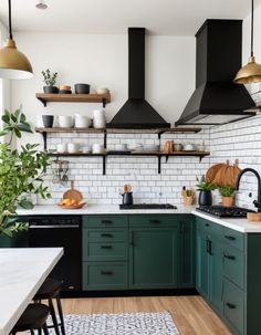 a kitchen with green cabinets and black stove top hoods over the range in front of an oven