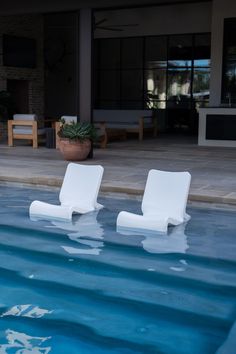 two white chairs sitting in the middle of a pool