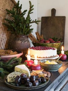 an assortment of cheeses, fruit and candles on a table