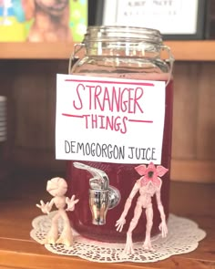 a jar filled with red liquid sitting on top of a table next to a sign