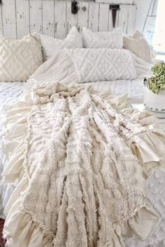 a white bed with ruffled bedspread and pillows