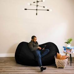 a man sitting on a bean bag chair in the living room looking at his cell phone