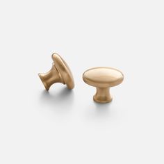 two brass knobs on white background with one in the middle and another in the back