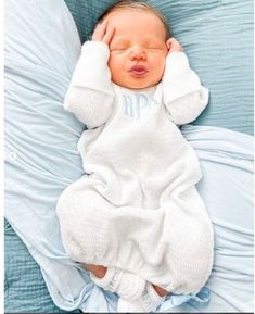 a baby wrapped in a blanket sleeping on top of a blue bedding with pillows