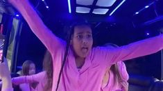 a girl in pink shirt holding up her arms