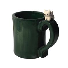 a green coffee mug with a white cat sitting on the inside of it's cup