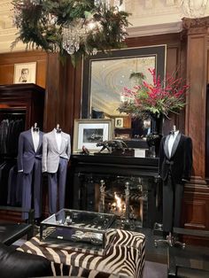 two men's suits are on display in front of a fireplace with zebra print foot stools