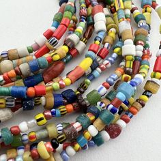 A long strand of vintage trade seed beads and Sand cast beads from Ghana in a lovely variety of Mixed African Trade Beads. Known as Christmas beads in the trade.  A really fun mixes of bright colors and interesting patterns and textures.  Our favorite way to wear them is on elastic wrapped around the wrist or waist or "as is" - a fun necklace. Approximate Bead Measurements: 24" of beads 28' with raffia 4-9mm diameter .8mm+ hole Traditional Colorful Beads For Crafting, Traditional Hand-strung Beads For Crafting, Vintage Multicolor Spacer Beads, Mixed Spacer Beads For Jewelry Making, Traditional Heishi Beaded Necklaces, Multicolor Hand-strung Beaded Necklaces With Oval Beads, Artisan Heishi Beads, Traditional Multicolor Oval Beaded Necklaces, Traditional Multicolor Oval Beads Necklace