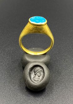 The Beautiful Gold Ring Probably From Ancient Greek's Time With Turquoise Color Blue Glass Stamp. A Beautiful Head Of A Man Figure Engraved On This Blue Glass. Seals Was Mostly Carved In Carnelian Or Garnet In Ancient Times But On Glass Very Rare. We Can Provide Gold Certificate On Customers Request.18 Karat Gold. We Provide Fast And Free Shipping World Wide. Luxury Blue Oval Cabochon Turquoise Ring, Luxury Blue Turquoise Ring For Formal Occasions, Blue Intaglio Ring As Gift, Blue Cabochon Signet Ring For Anniversary, Luxury Blue Oval Cabochon Ring, Luxury Blue Ring With Oval Cabochon, Blue Oval Hallmarked Signet Ring, Luxury Blue Ring With Bezel Setting, Blue Cabochon Signet Ring