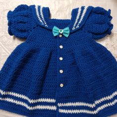 a crocheted blue dress with white stripes and a bow