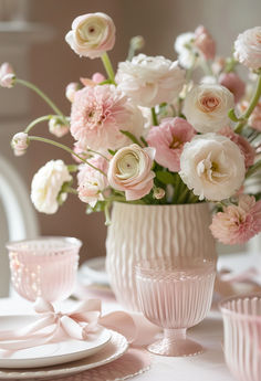 a vase filled with lots of pink and white flowers on top of a table next to cupcakes