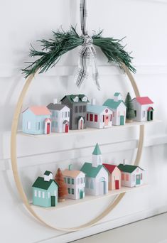 a circular shelf with wooden houses on it and a bow hanging from the top one