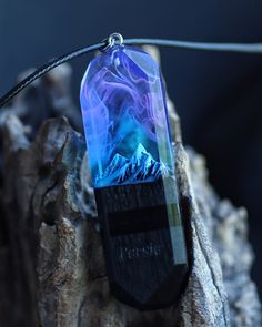 a piece of glass sitting on top of a wooden tree stump with a mountain in the background