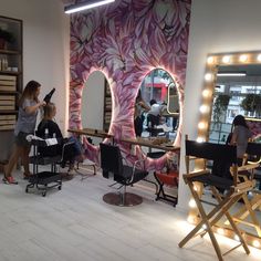 a woman is getting her hair done in front of a mirror with lights on it