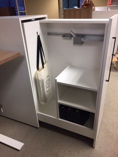 an open white cabinet with a bag hanging from it