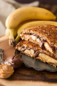 two bananas and some chocolate on a plate with peanut butter in the middle, next to it is a banana split