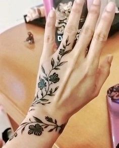 a woman's hand with a flower tattoo on it