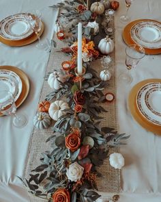 the table is set for thanksgiving dinner with white and orange flowers, pumpkins and candles