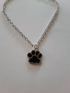 a small dog paw charm on a silver chain with a black cat's paw in the center