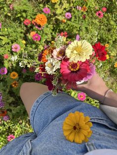 a person laying on their stomach holding a bouquet of flowers in front of some wildflowers