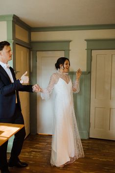 the bride and groom are dancing together in their wedding day attire, with one holding his hand out