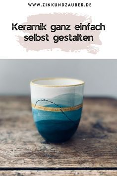 a cup sitting on top of a wooden table next to a sign that says keramik ganz enfach sebes gestatten