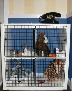 three cages with stuffed animals in them on top of a shelf next to a phone