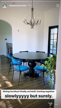 a dining room table with blue chairs and a chandelier