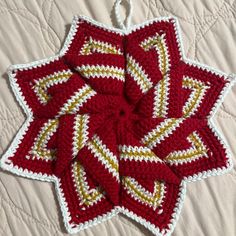 a red and white crocheted star ornament sitting on top of a bed