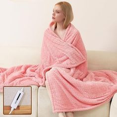 a woman sitting on a couch wrapped in a pink blanket