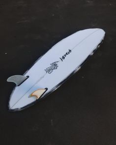 a white surfboard with writing on it laying on the ground