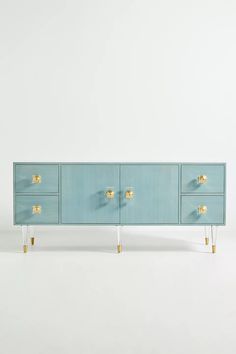 a blue cabinet with two gold handles and three drawers on each side, against a white background