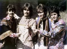 the rolling stones pose for a photo in front of a brick wall wearing colorful clothing