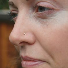 a close up of a woman with a nose piercing on her nose and one eye open