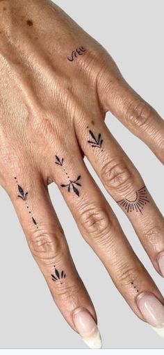 a woman's hand with tattoos on it and the fingers are shown in black ink