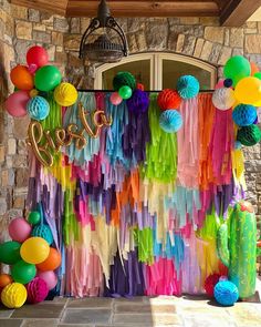 there is a colorful backdrop with balloons and streamers on the front door for a fiesta party