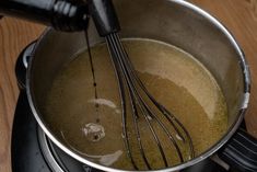 a pot filled with liquid and whisk on top of a stove