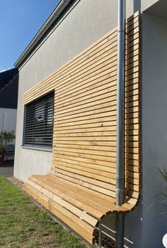 a wooden bench sitting in front of a building next to a flower potted plant